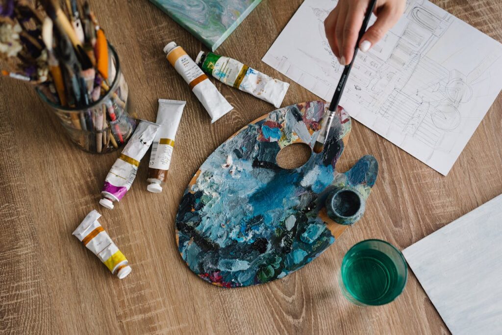 An artistic setup with paint tubes, palette, and brushes ready for a creative painting session.